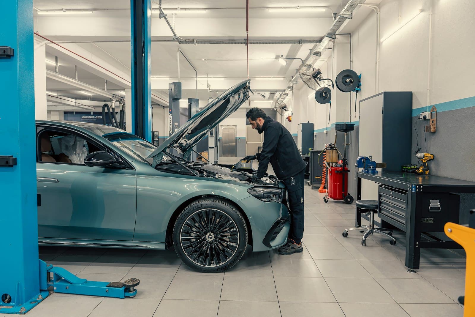 A mechanic working under the bonnet of a car in a workshop