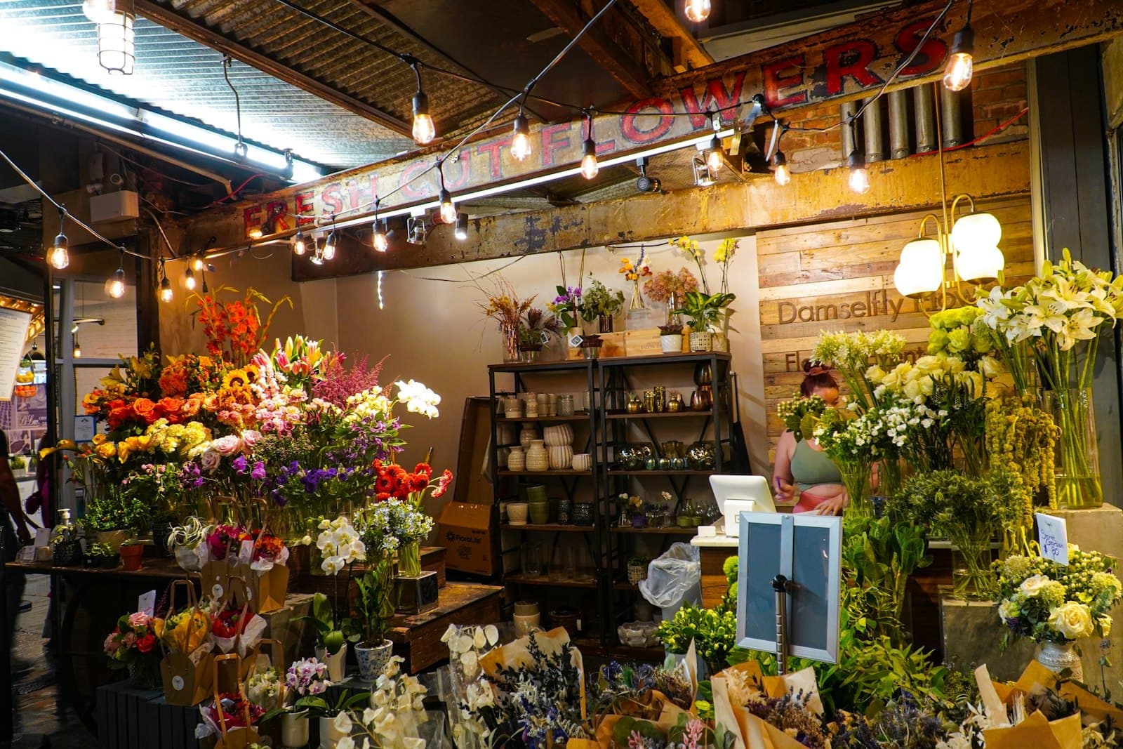 A flower shop full of bouquets under string lights.