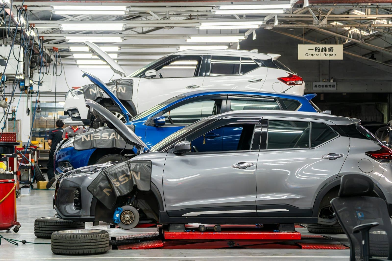 Cars up on lifts in a bright auto repair workshop.