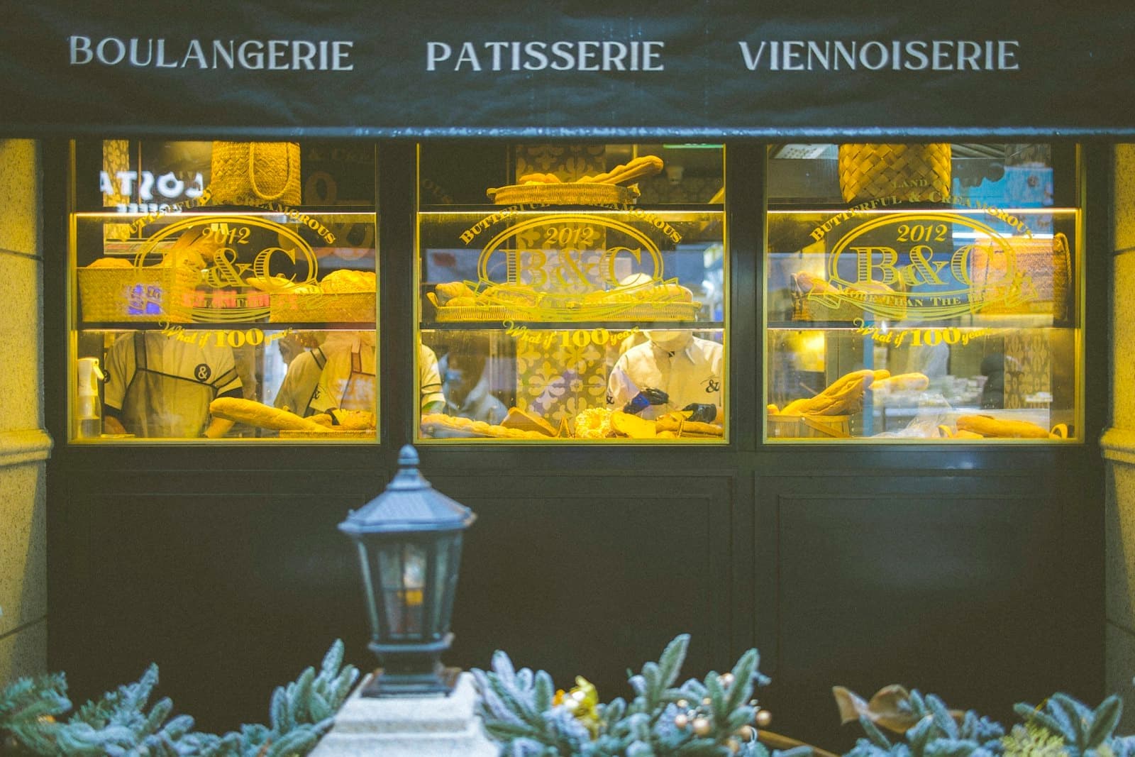 A bakery window lit up at night, bread on the shelves.