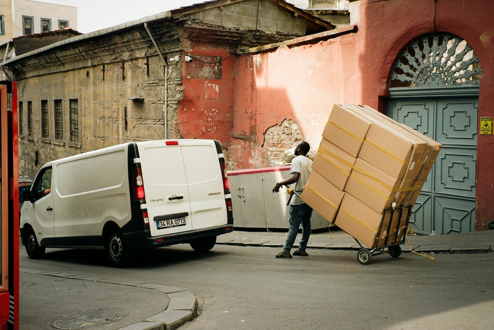A mover wheels a stack of boxes to a white van.
